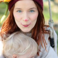 Clown Zausel schaukelt mit kleinem Baby im Arm