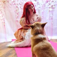 rothaarige kleine Meerjungfrau im rosa Ballkeid schmust mit Hund